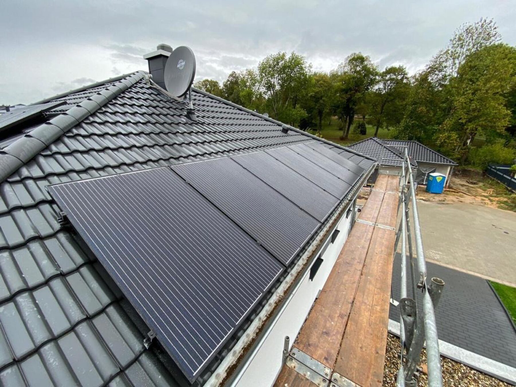 Schwarze PV-Module auf anthrazit Pfannendach mit Schornstein