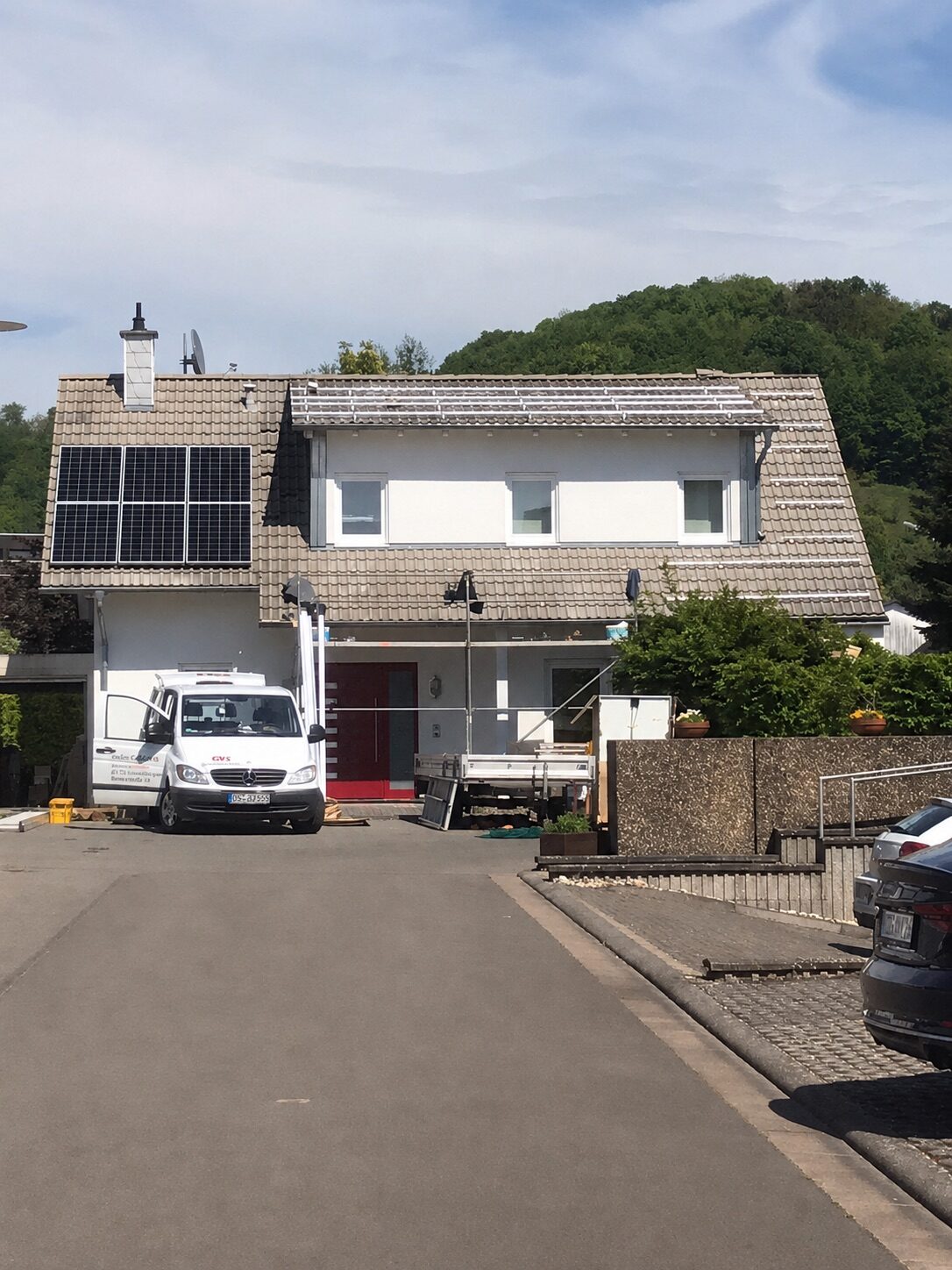 Wohnhaus mit PV-Modulen und Mitarbeitern auf dem Dach