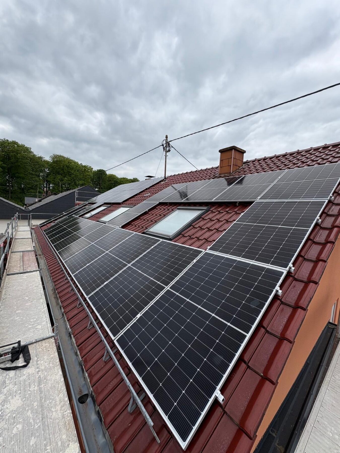 Schwarze PV-Module auf rotem Pfannendach mit Schornstein